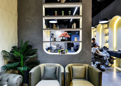 Stylish interior of L8 Elite Barbershop in Riyadh, with modern decor and barber at work.