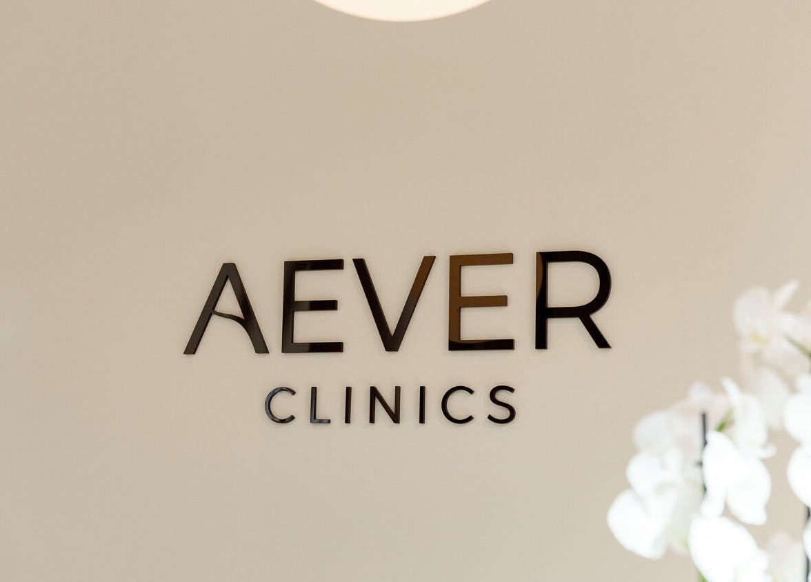 Elegantes Logo von Aever Clinics - Berlin Am Tacheles, Berlin, Berlin, DE neben weißen Orchideen.