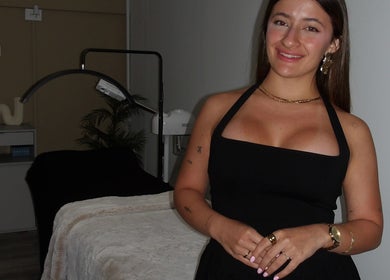 Profesional en Skin Diary, Toa Baja, PR, junto a camilla en elegante sala de bienestar.