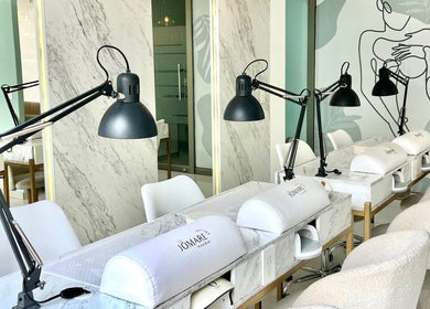 Interior elegante de Nail Spa Jomare en Zapopan, Jalisco, MX con mesas de mármol y lámparas modernas.