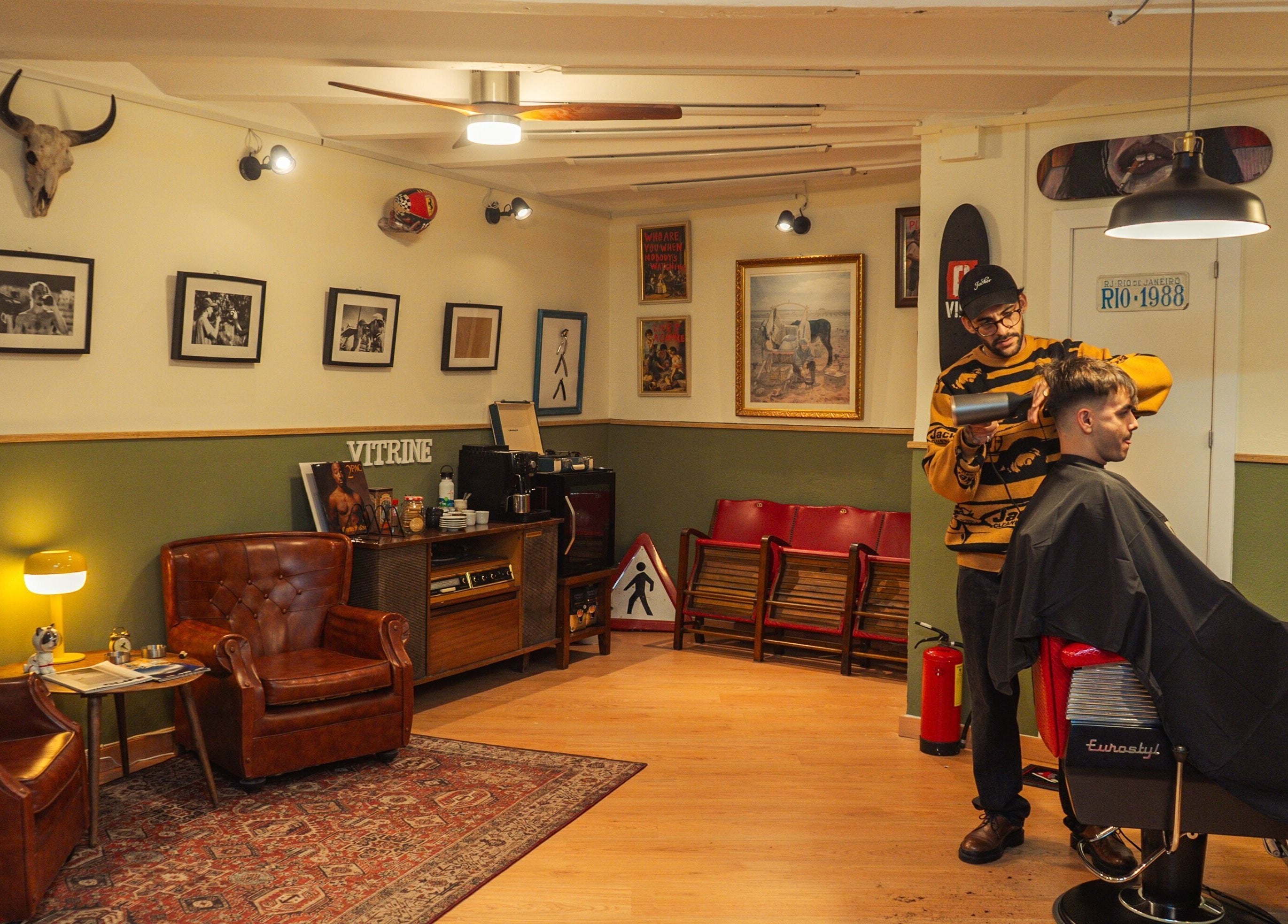 Interior de Vitrine Tradicional Barber en Barcelona, Catalunya, ES, con cliente recibiendo un corte de pelo.