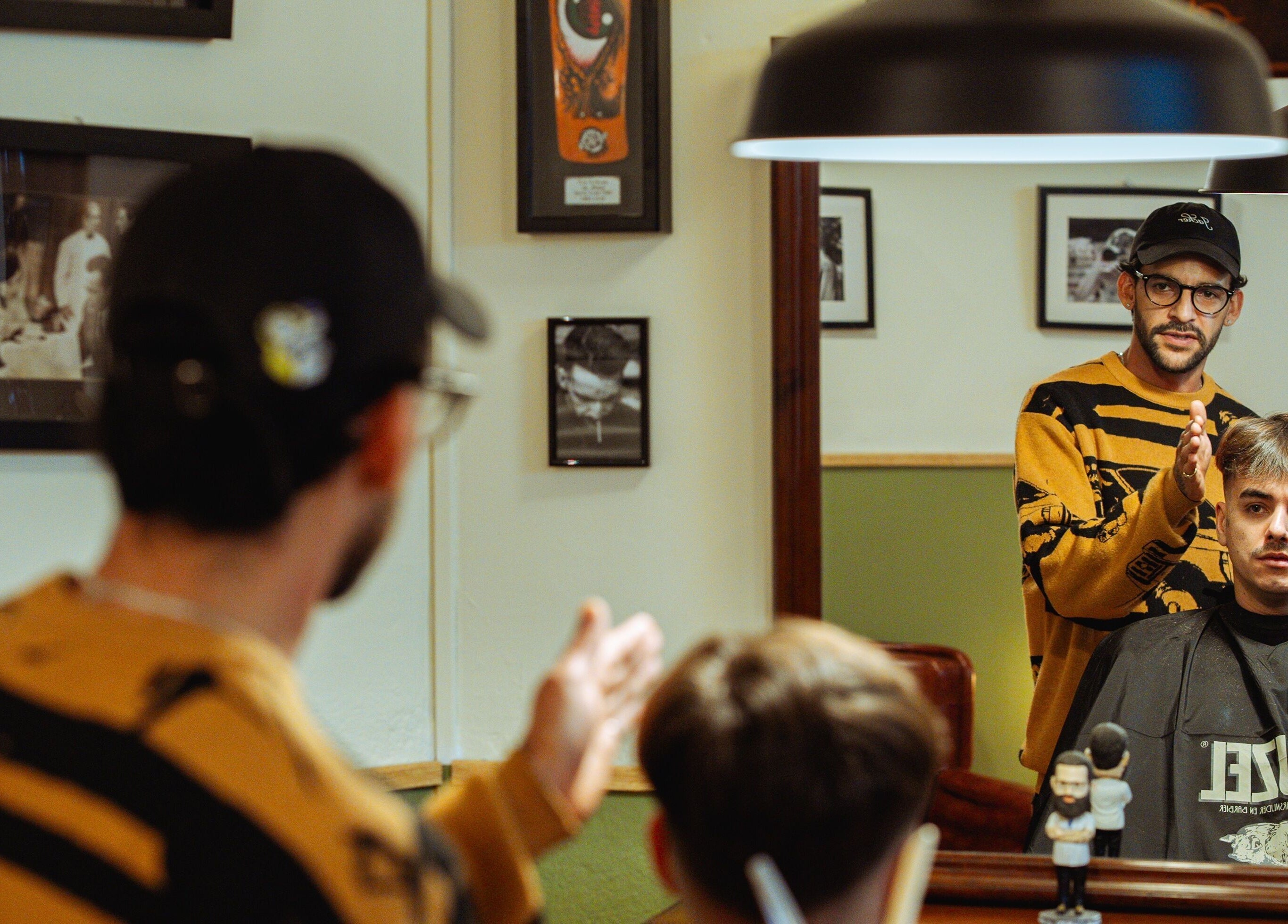 Interior de Vitrine Tradicional Barber en Barcelona, Catalunya, ES con cliente recibiendo corte de pelo.