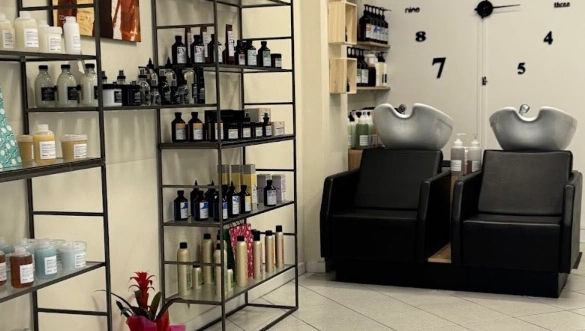 Interno di Hair Salon di Creatura Giada a Modena, Emilia-romagna, IT, con prodotti esposti e sedie lavatesta.