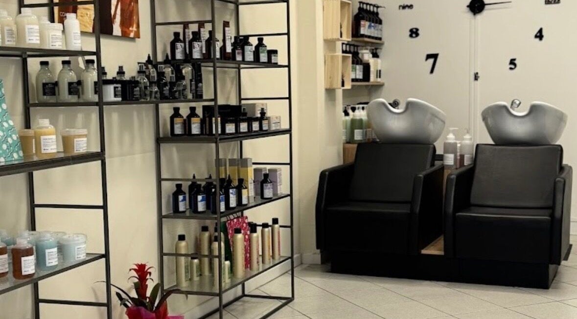 Interno di Hair Salon di Creatura Giada a Modena, Emilia-romagna, IT, con prodotti esposti e sedie lavatesta.