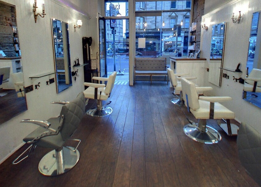 Stylish interior of Hair by Boom salon in Edinburgh, Scotland, GB with sleek chairs and large mirrors.