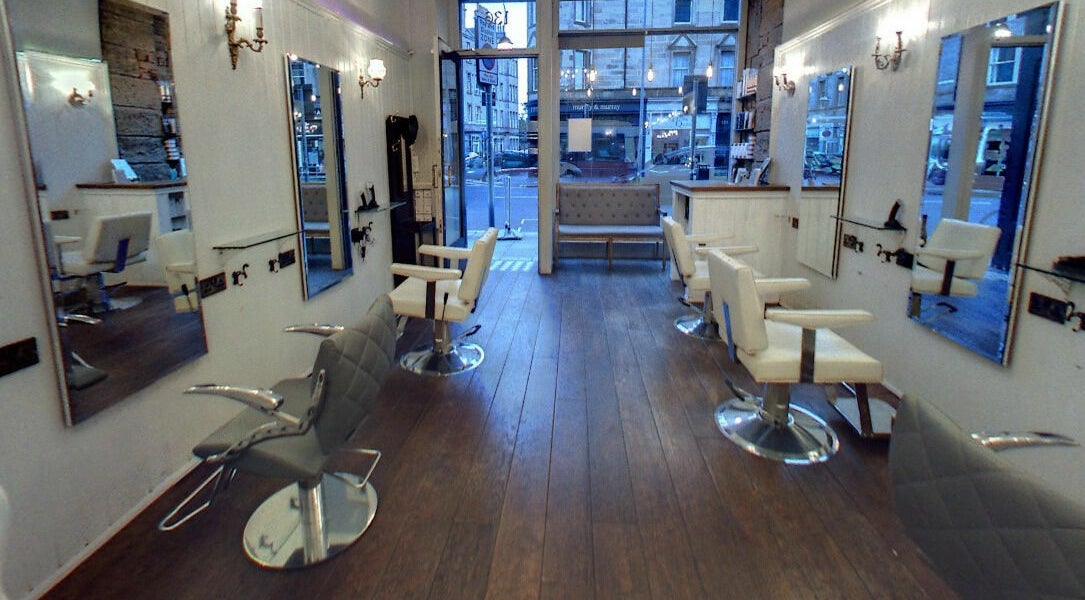 Stylish interior of Hair by Boom salon in Edinburgh, Scotland, GB with sleek chairs and large mirrors.