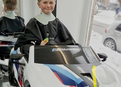 Enfant dans une voiture-jouet au salon Lamitta - Salon de Coiffure et Barbier, Montréal, Québec, CA.