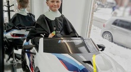 Enfant dans une voiture-jouet au salon Lamitta - Salon de Coiffure et Barbier, Montréal, Québec, CA.