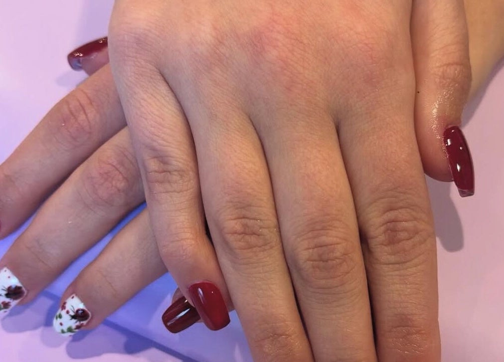 Elegant nail art with red and floral accents at Paris Salon, Ridgefield, Connecticut, US.