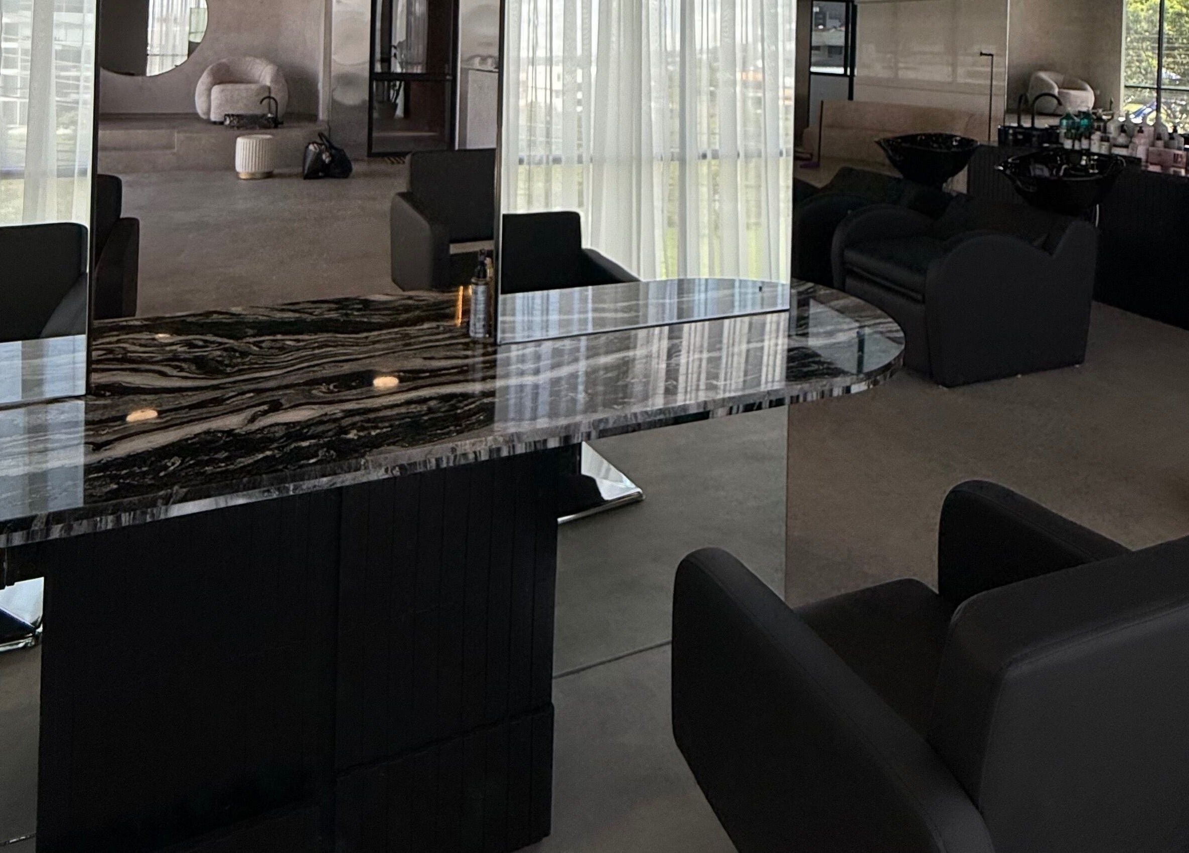 Sala moderna en Zūl Beauty, Quito, Pichincha, EC con sillas negras y mesa de mármol bajo luces suaves.