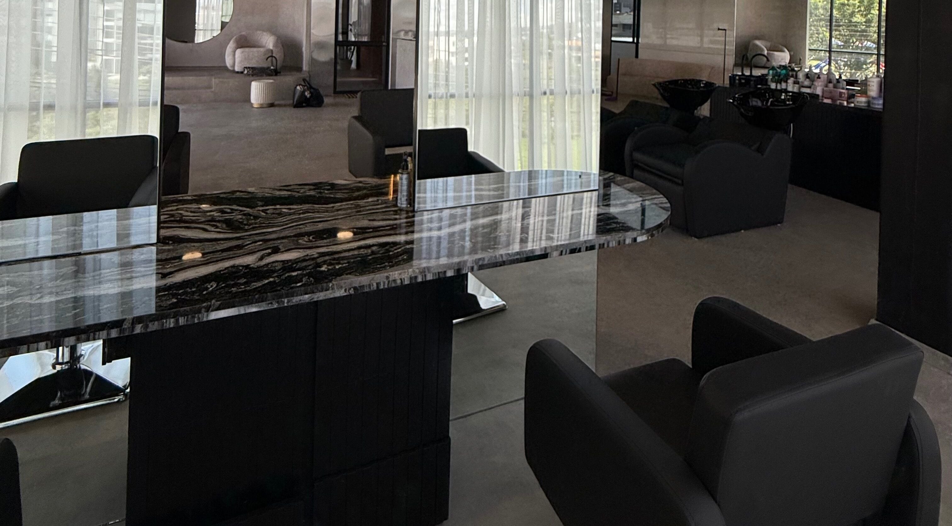 Sala moderna en Zūl Beauty, Quito, Pichincha, EC con sillas negras y mesa de mármol bajo luces suaves.