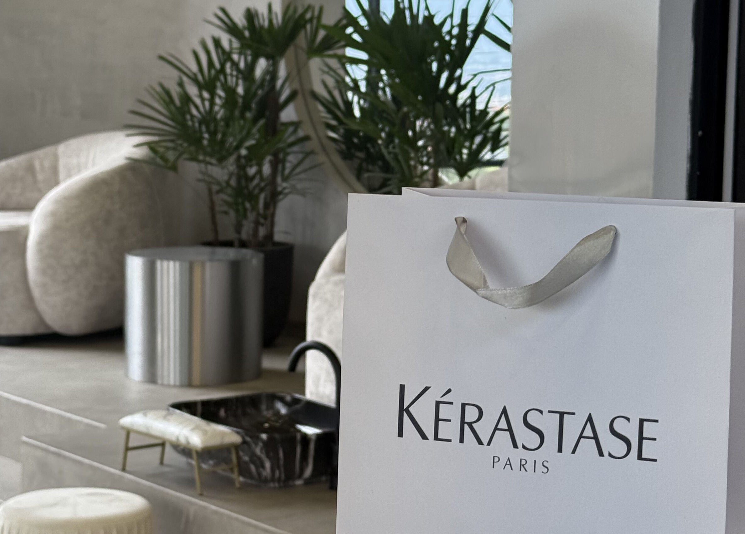 Bolsa de Kerastase en Zūl Beauty, Quito, Pichincha, EC con un elegante fondo de plantas y sillón.