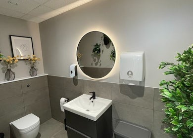Elegant bathroom at By Serwah Wellness Wimbledon, London, England, GB with plants and round mirror.