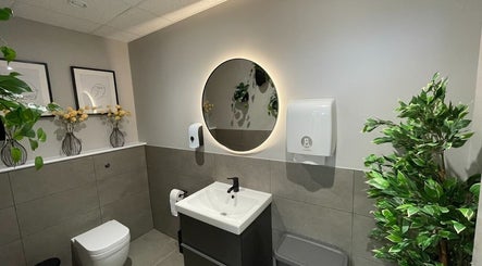 Elegant bathroom at By Serwah Wellness Wimbledon, London, England, GB with plants and round mirror.