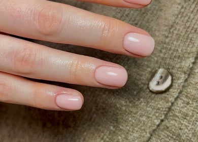 Elegant nude manicure at Olive Studio, Mansfield, England, GB. Perfectly polished nails on a textured background.