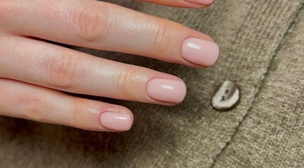 Elegant nude manicure at Olive Studio, Mansfield, England, GB. Perfectly polished nails on a textured background.