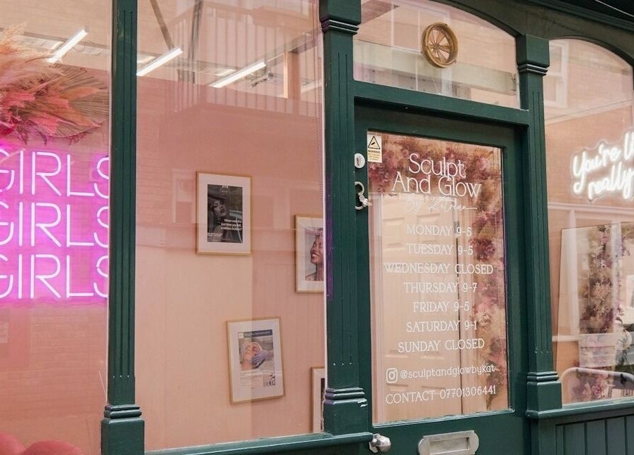 Front of Sculpt and Glow by Katrina in Brentwood with pink neon sign and service hours.