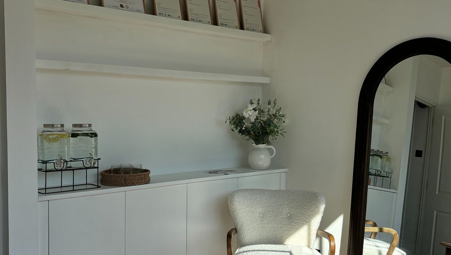 Elegant waiting area at Skin Diary By Toyah, London, England with plush chair, flowers, and refreshment jars.