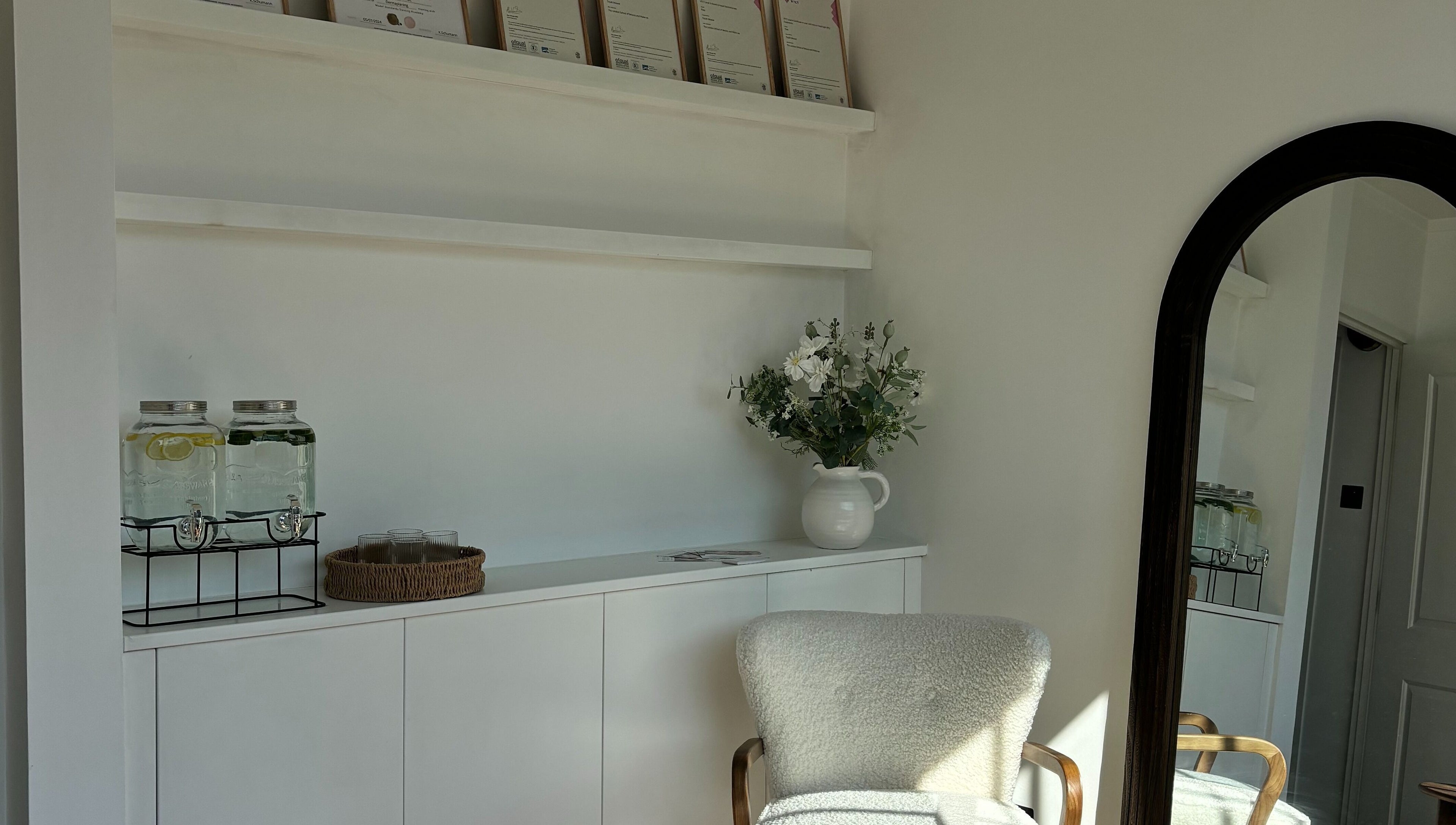 Elegant waiting area at Skin Diary By Toyah, London, England with plush chair, flowers, and refreshment jars.