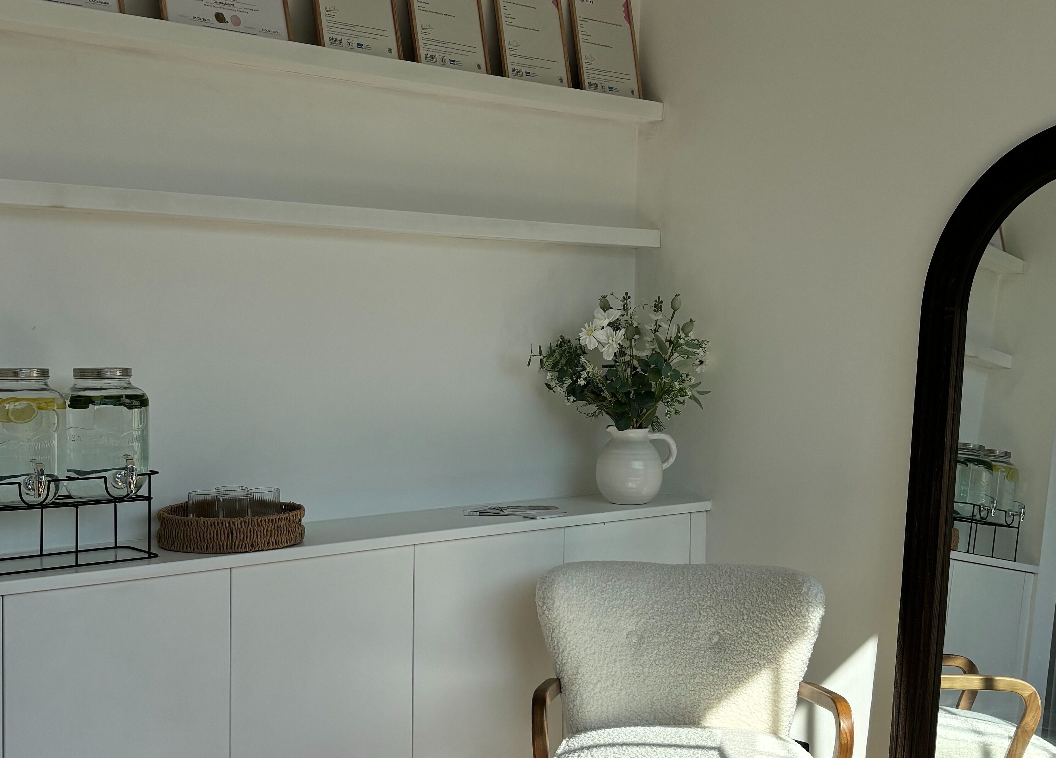 Elegant waiting area at Skin Diary By Toyah, London, England with plush chair, flowers, and refreshment jars.
