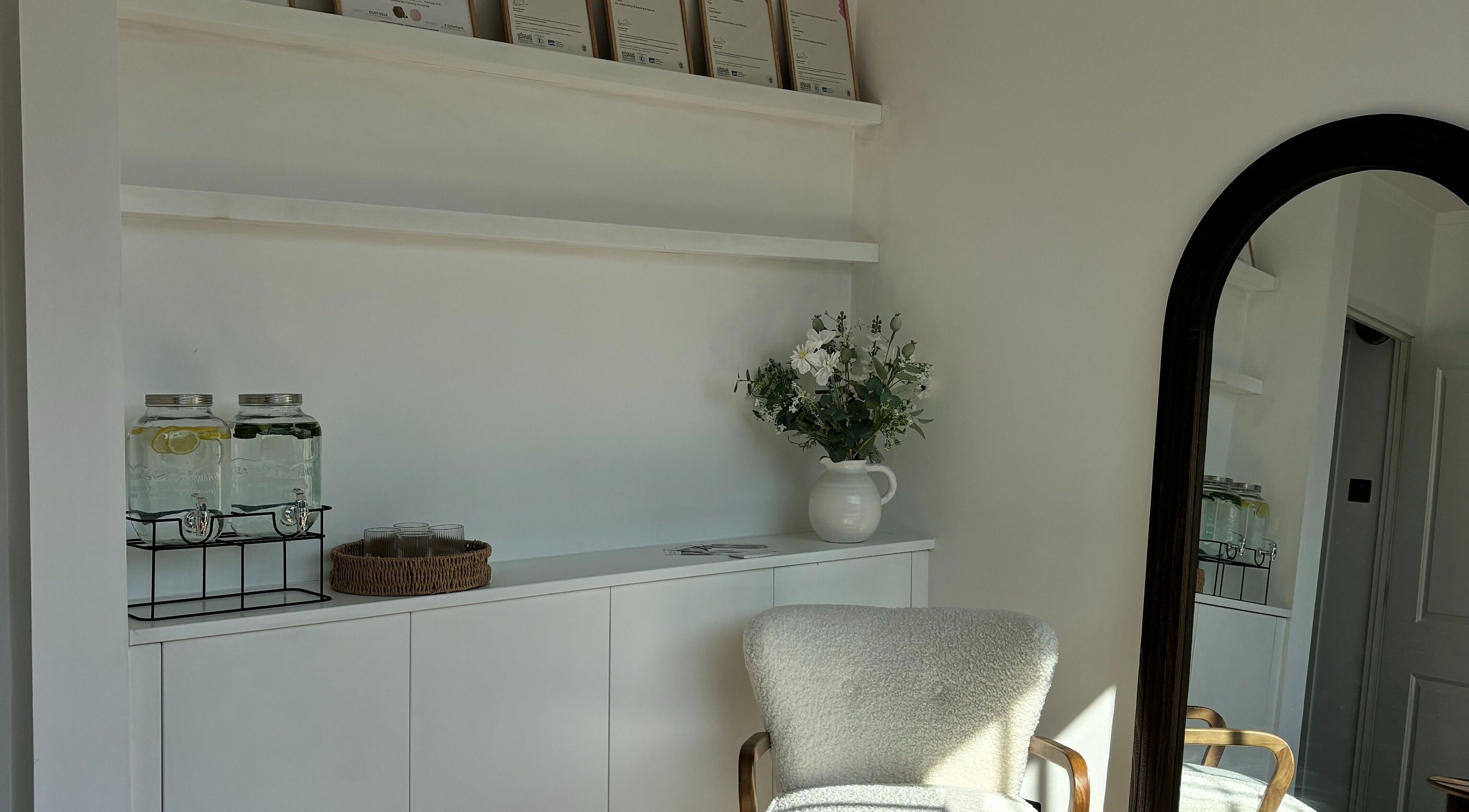 Elegant waiting area at Skin Diary By Toyah, London, England with plush chair, flowers, and refreshment jars.