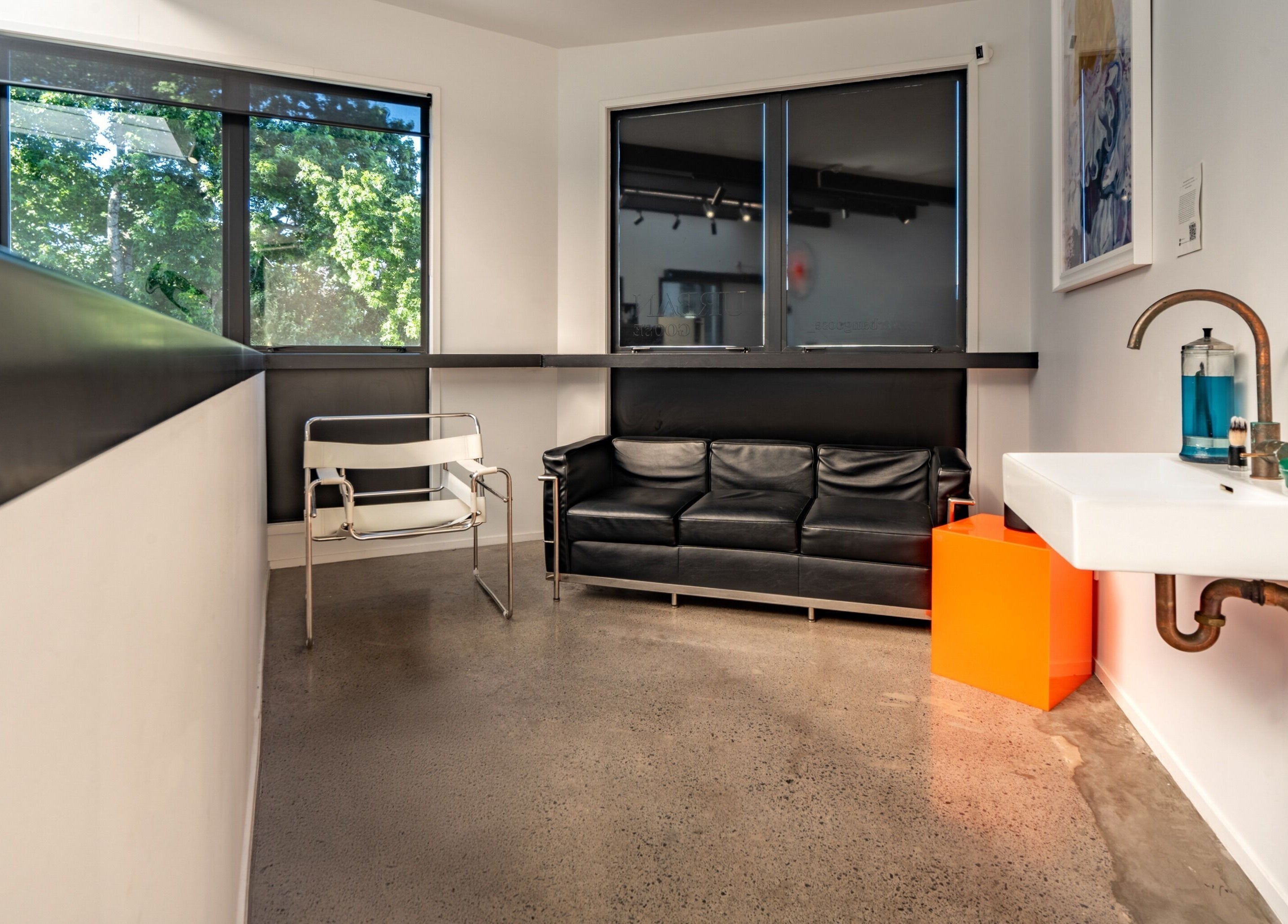 Modern waiting area at Urban Goose, Auckland, Auckland, NZ, featuring black sofa, chair, and vibrant decor.