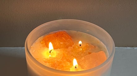 Three glowing candles on crystals at Goddess Rising Hair Extensions, Belper, England, GB create a calming ambiance.
