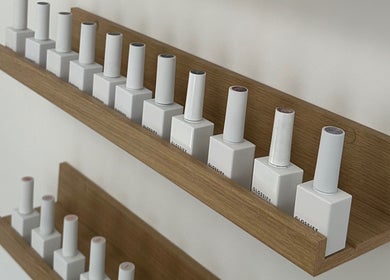 Nail polish lineup at Muse Beauty Studio, Port Talbot, Wales, GB, featuring neatly arranged bottles on wooden shelves.