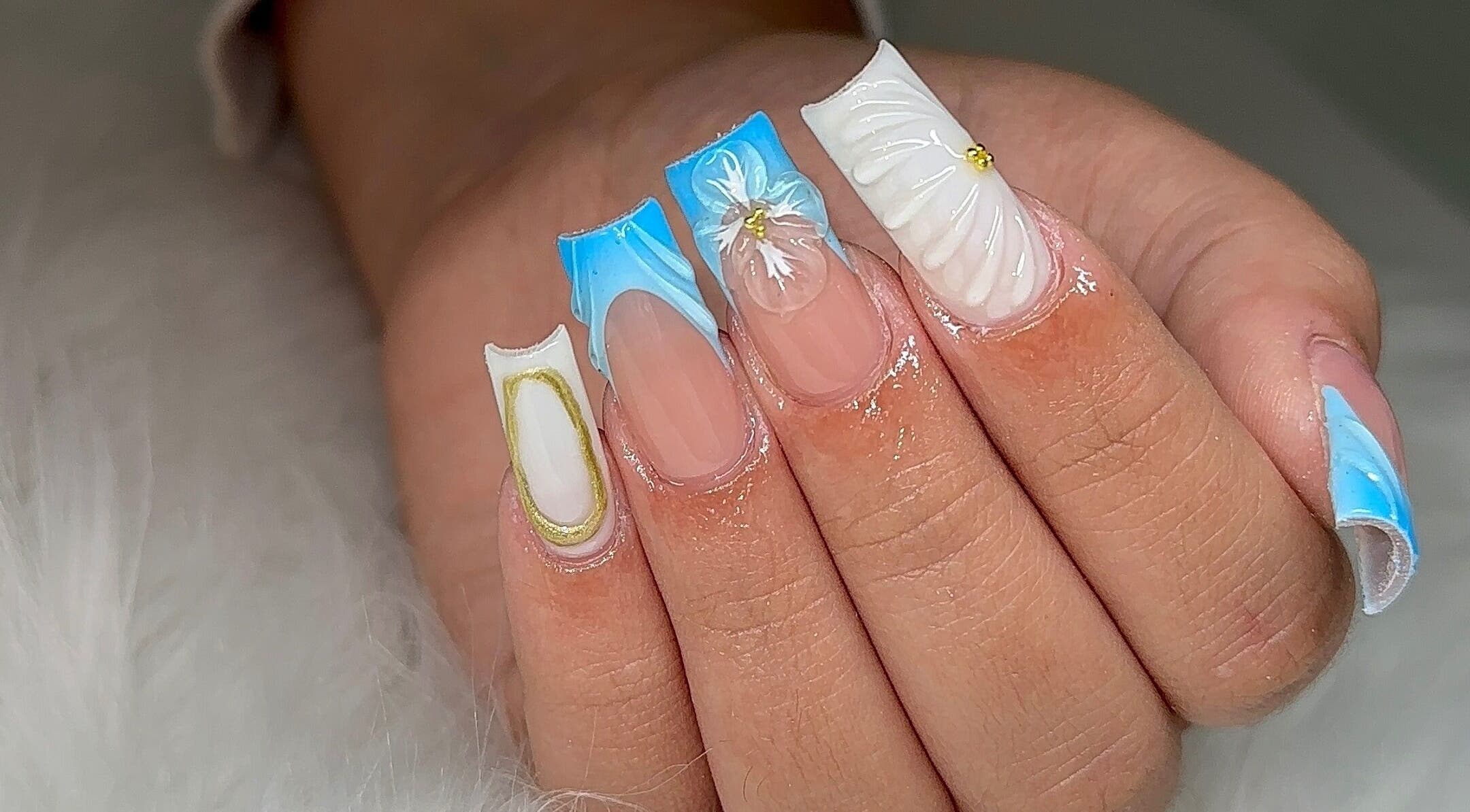 Elegant nail art at Fantasy Nails Miami, showcasing intricate blue and white designs, located in Miami, Florida, US.