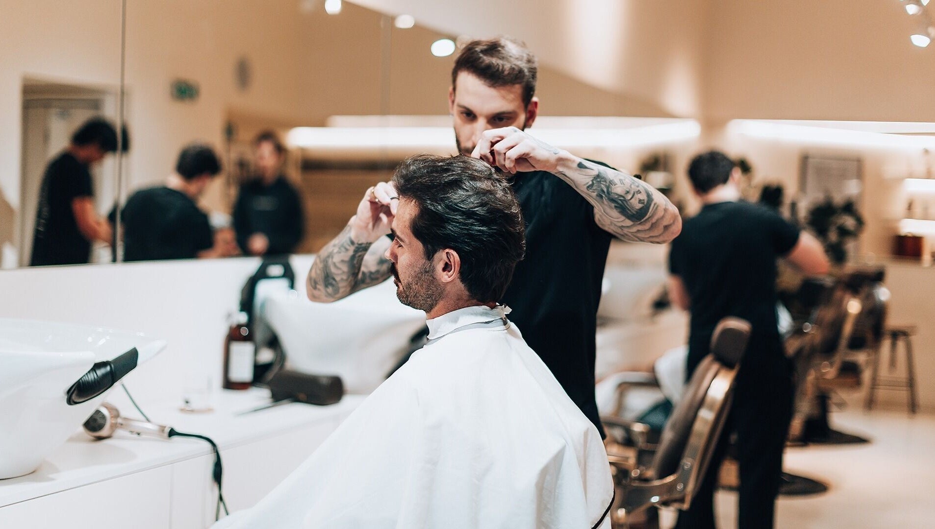 Stylist at Barbieri Barbershop & SPA in Lisboa, Lisboa, PT expertly cutting a man's hair in a modern, elegant salon.