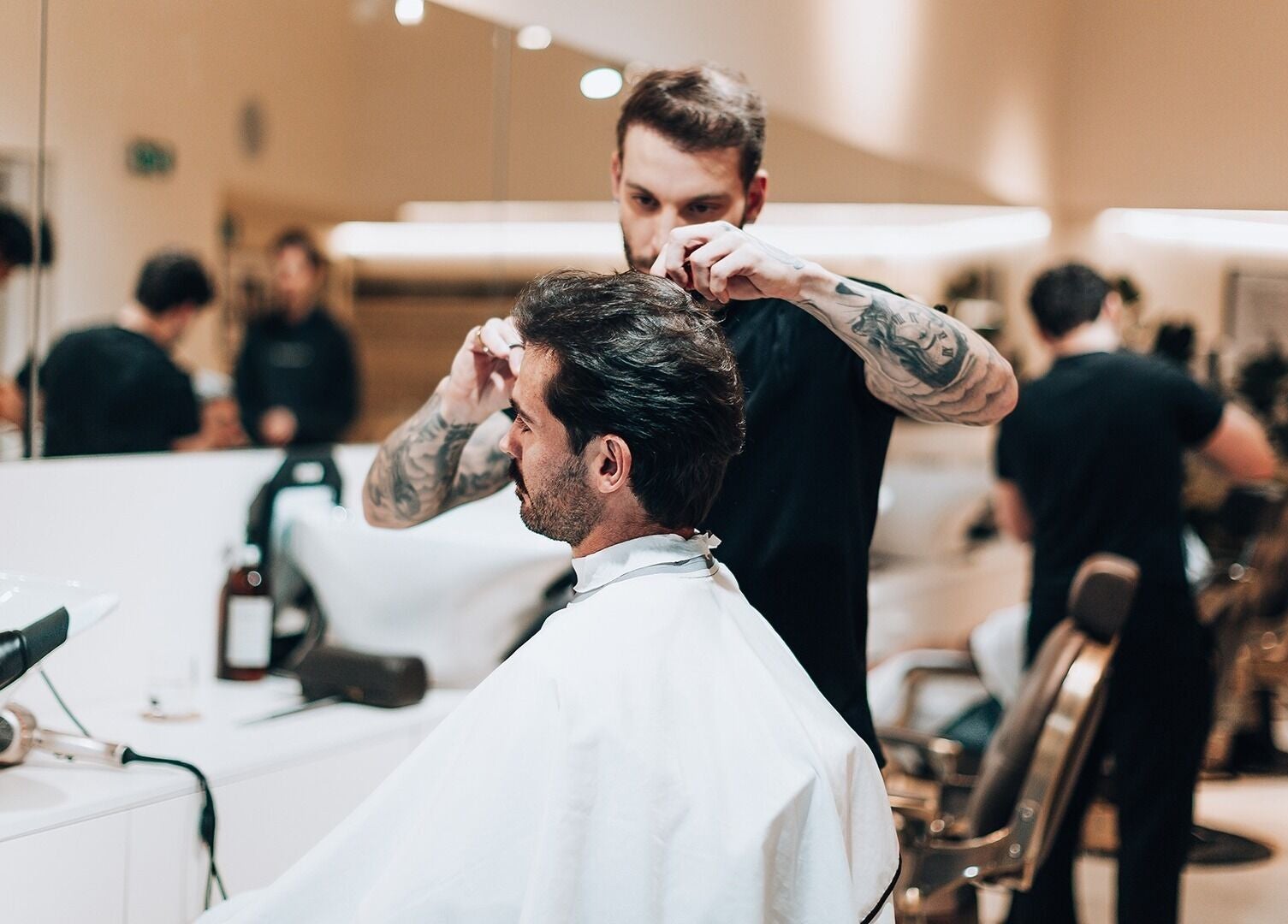 Stylist at Barbieri Barbershop & SPA in Lisboa, Lisboa, PT expertly cutting a man's hair in a modern, elegant salon.