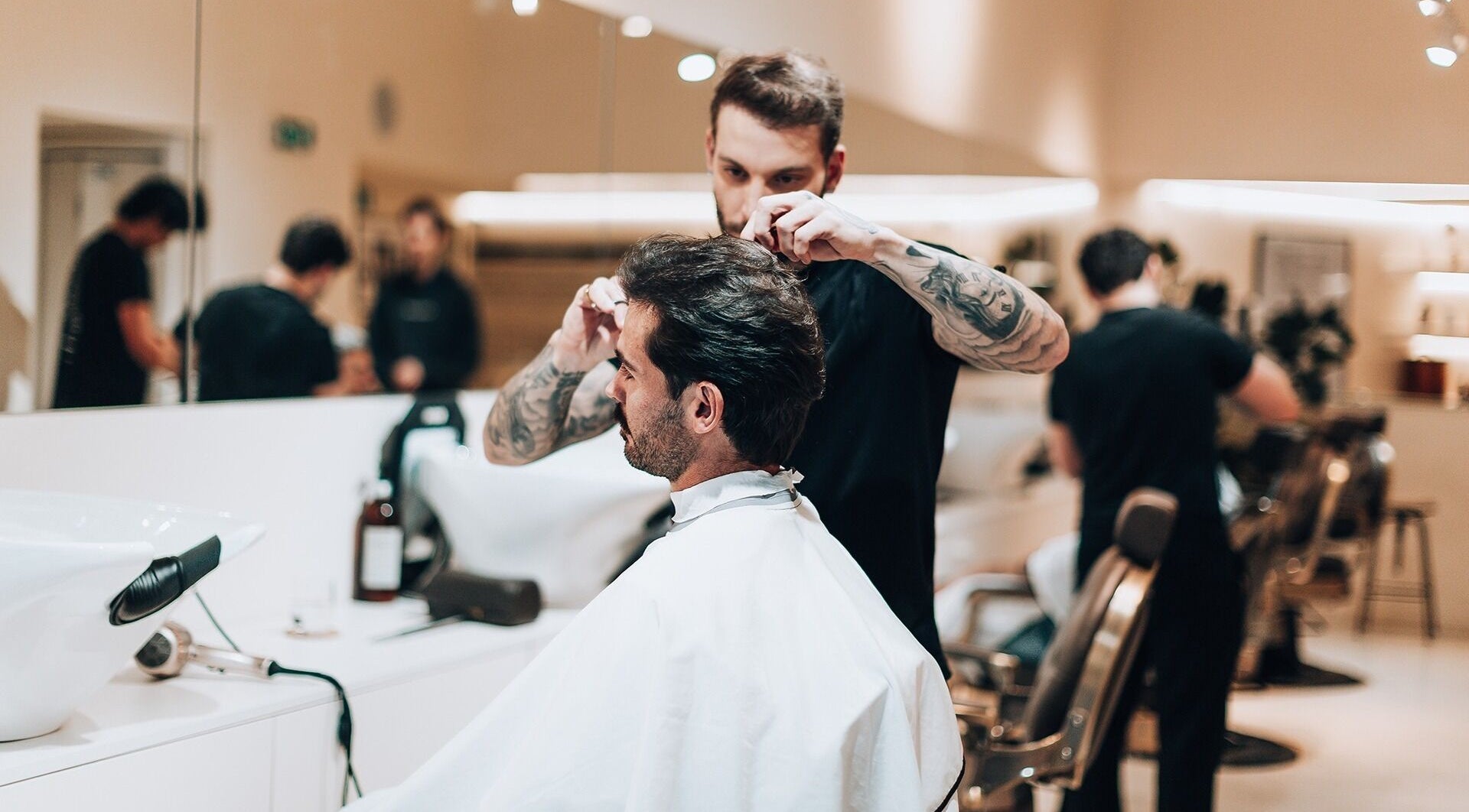 Stylist at Barbieri Barbershop & SPA in Lisboa, Lisboa, PT expertly cutting a man's hair in a modern, elegant salon.