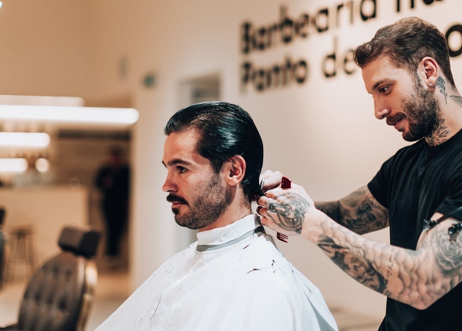 Barber giving a stylish haircut at Barbieri Barbershop & SPA, Lisboa, Lisboa, PT. Modern chairs in the background.
