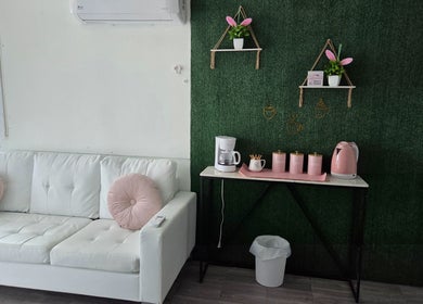 Sala de espera en Koquetinas Studio, Las Piedras, PR, con sofá blanco y detalles rosados.