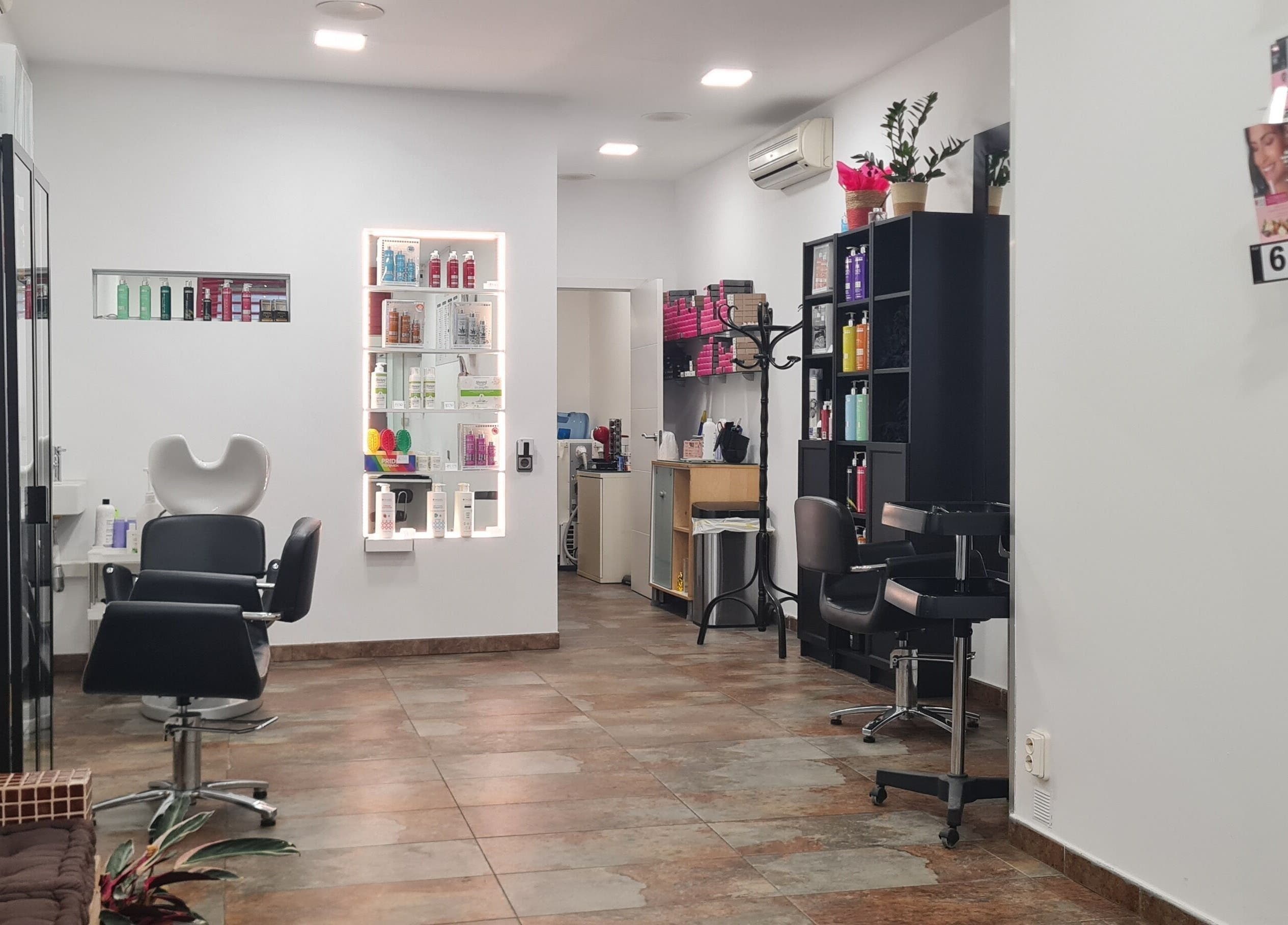 Interior del salón Nuska en Barcelona, Catalunya, ES con sillas y estantes de productos de belleza.