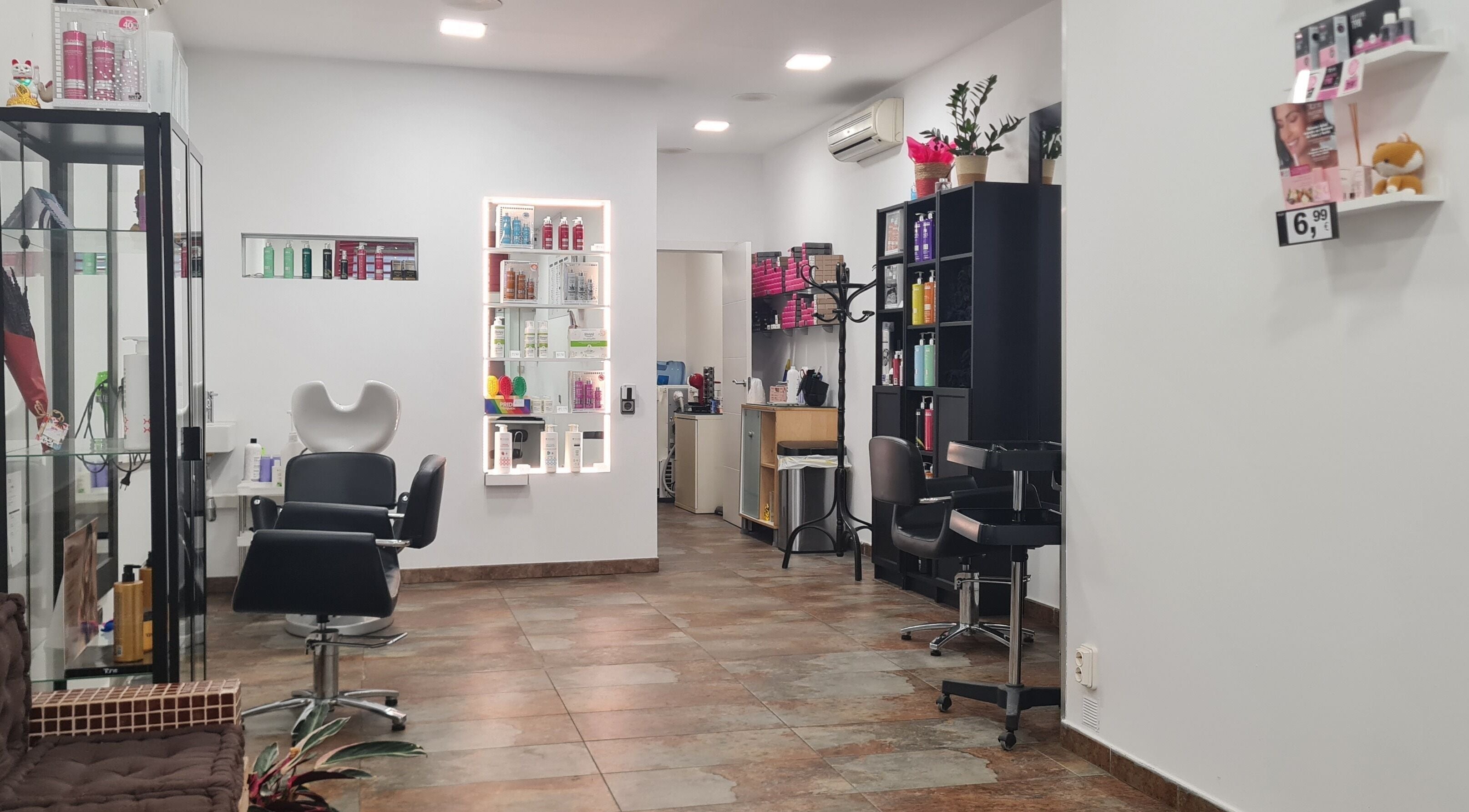 Interior del salón Nuska en Barcelona, Catalunya, ES con sillas y estantes de productos de belleza.