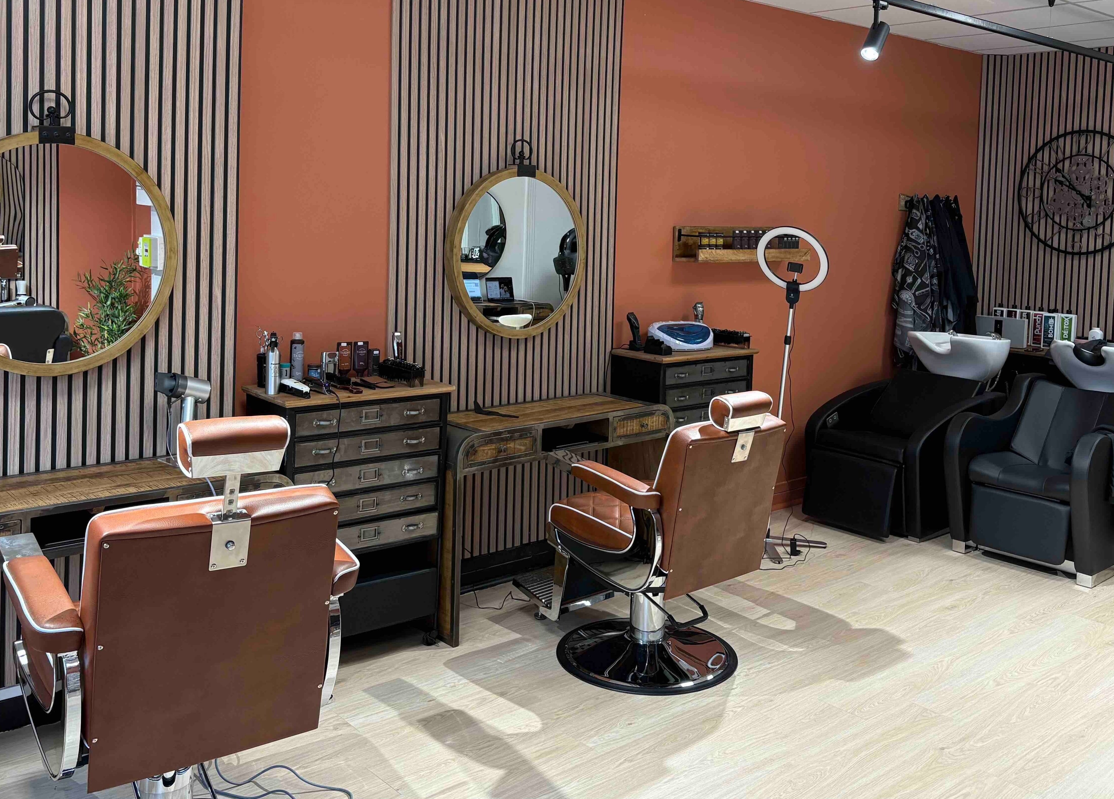 Salon Alexandre à Audruicq, Hauts-de-France, FR avec sièges en cuir et miroirs ronds élégants.