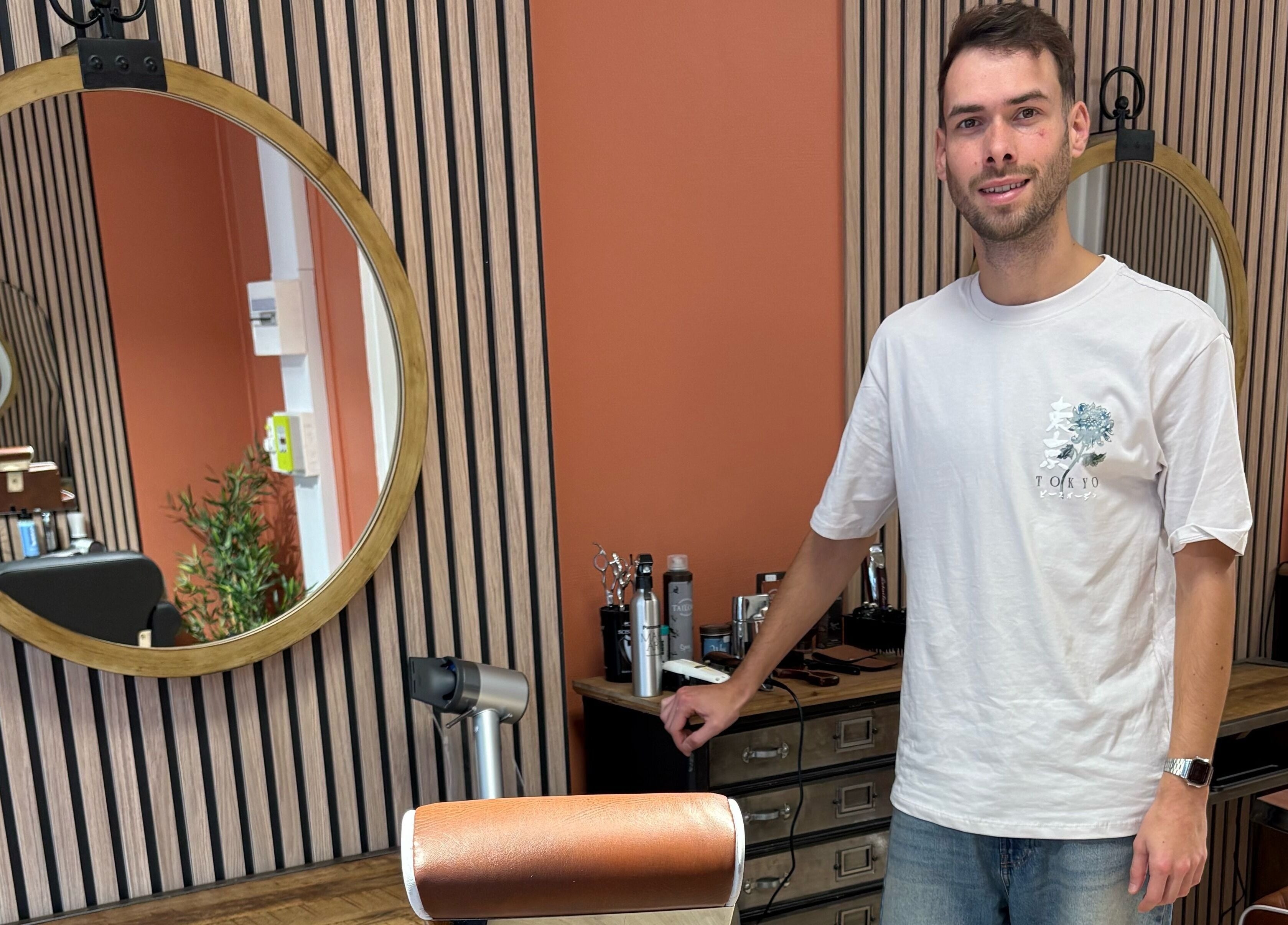 Homme souriant dans Salon Alexandre, Audruicq, Hauts-de-France, FR avec miroir rond et outils de coiffure.