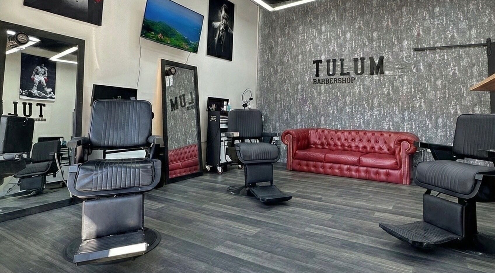 Interior elegante de Tulum Barbershop Barbería CDMX en Ciudad De México, MX con sillas de barbería y sofá rojo.