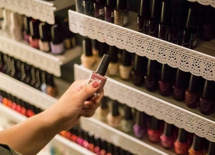 A hand selects nail polish at Paradise Spa and Coffee Bar, East Saint Paul, Manitoba, CA.