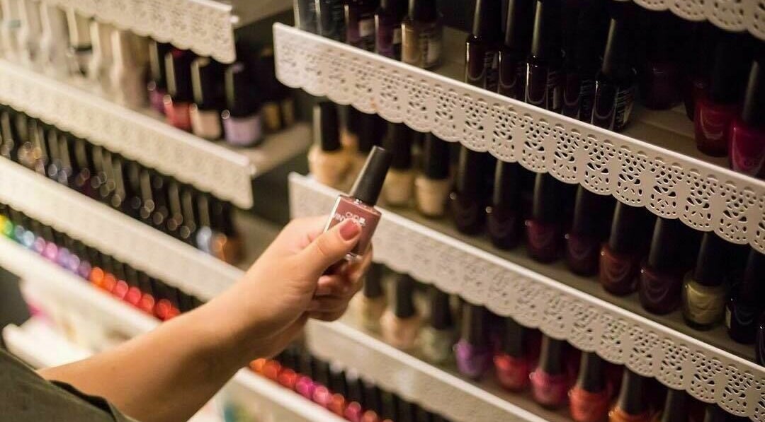 A hand selects nail polish at Paradise Spa and Coffee Bar, East Saint Paul, Manitoba, CA.