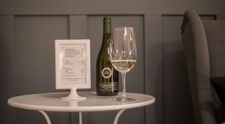 Wine and glass on table at Paradise Spa Hair, East Saint Paul, Manitoba, CA, offering a cozy ambiance.