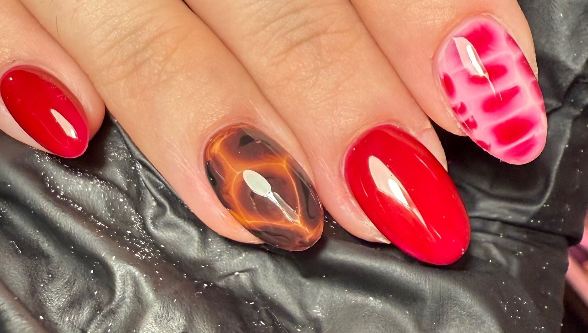 Trendy nail art at Sofs Beauty Bar, Dowlais, Cymru, GB showcasing vibrant red and marbled designs.
