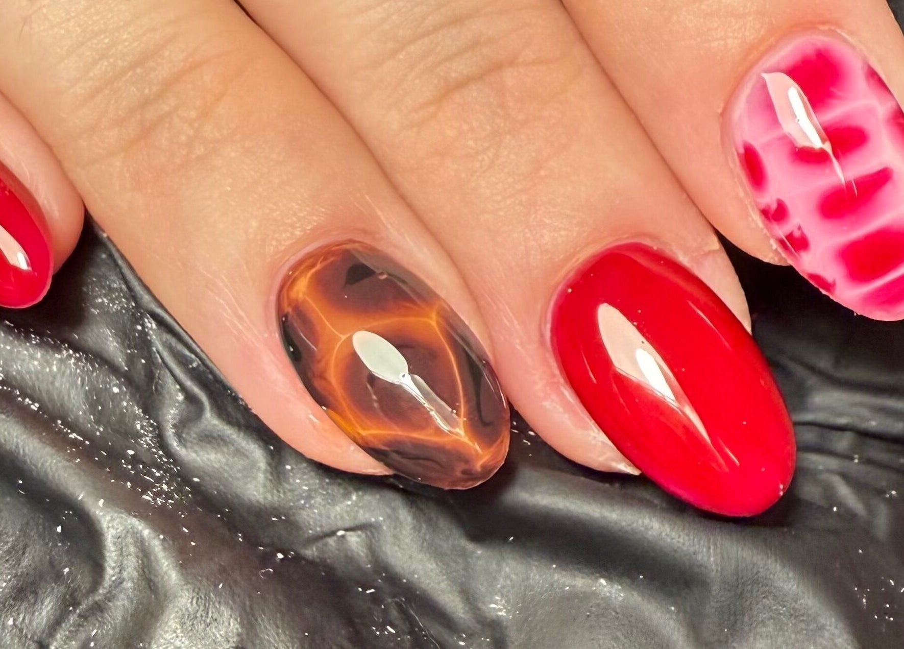 Trendy nail art at Sofs Beauty Bar, Dowlais, Cymru, GB showcasing vibrant red and marbled designs.
