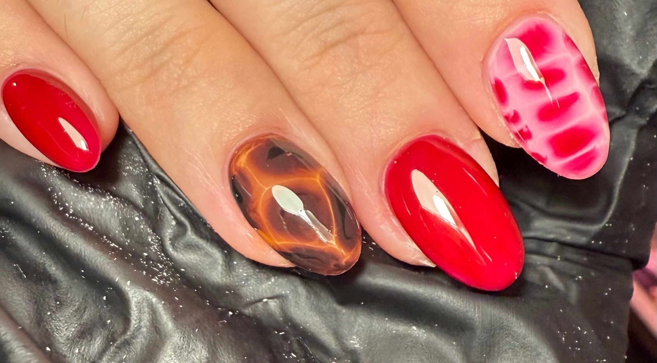Trendy nail art at Sofs Beauty Bar, Dowlais, Cymru, GB showcasing vibrant red and marbled designs.