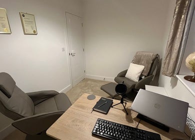 Cozy therapy room at Emily Bentham Hypnotherapy, Leicestershire, England, GB with comfortable chairs and a desk.