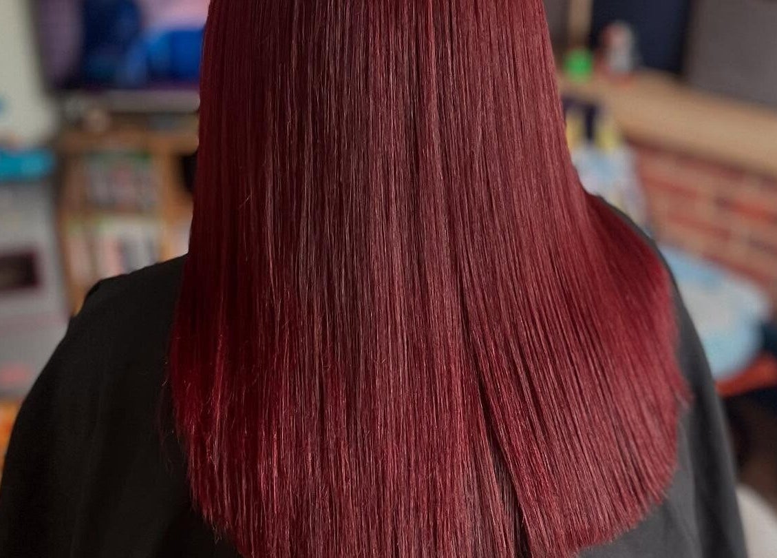 Vibrant ruby red hair styled at Bendall Beauty, Farnborough, England, GB, showcasing sleek and shiny finish.
