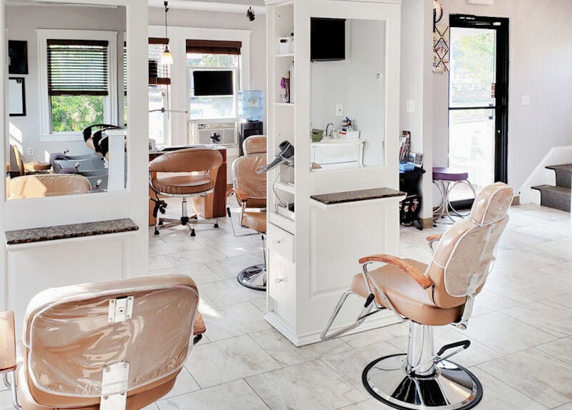 Bright, modern salon interior at Skin Deep Skin, Quincy, Massachusetts, US, featuring plush chairs and large mirrors.