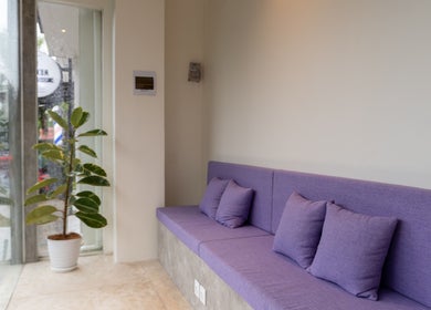 Relaxing purple seating at Muscle Works, Bali, Bali, ID, inviting atmosphere with potted plant and glass window.