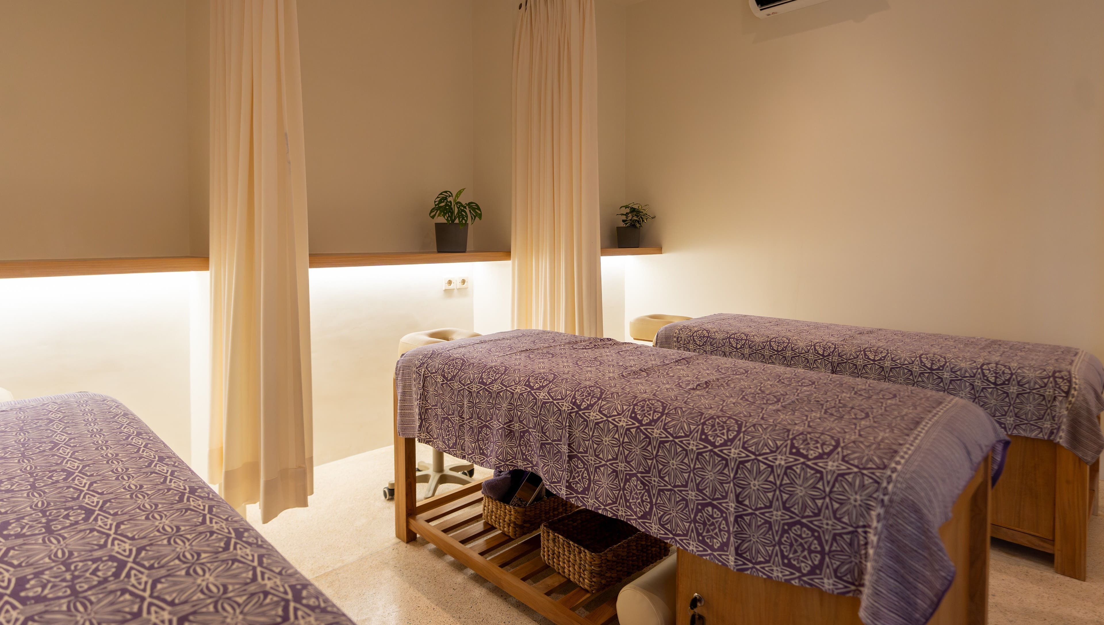 Relaxing massage room at Muscle Works, Bali, ID with two beds and calming decor.